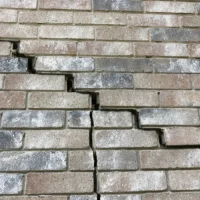 Stair-step crack in a brick wall, a sign of foundation damage