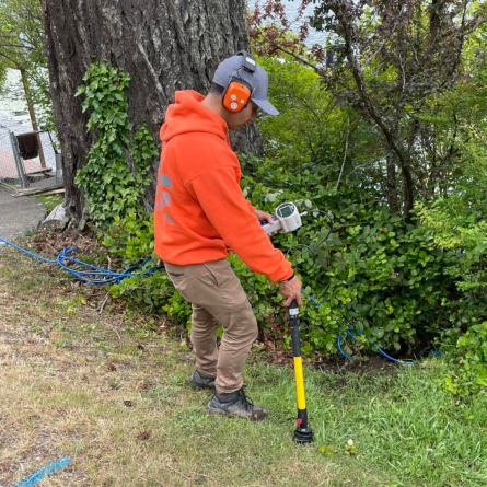 Isaac White using leak detection equipment to pinpoint an underground water leak